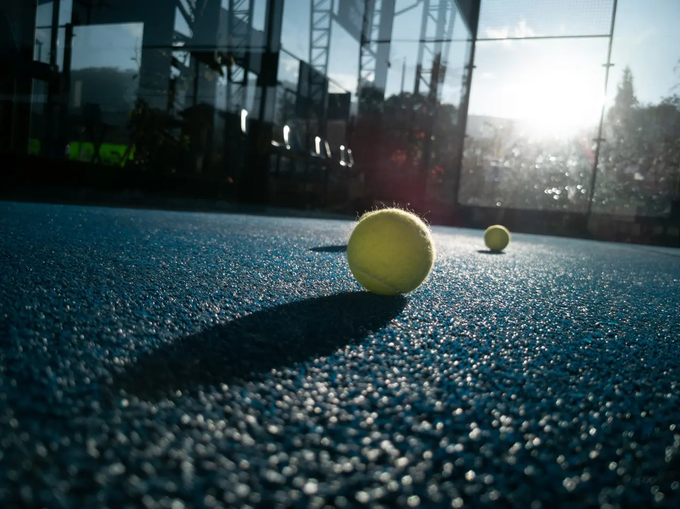 Padelball vor einer Glaswand im Gegenlicht